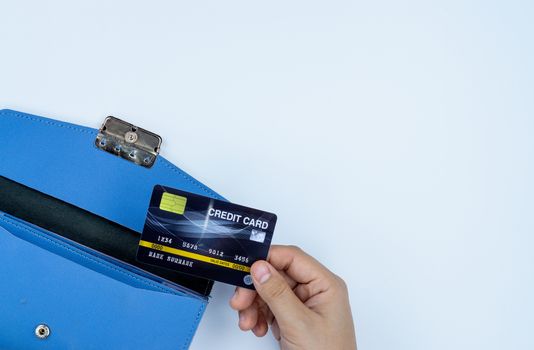 Woman hand taking out the credit card from blue purse for payment on the white background. Finance and money concept, top view, copy space for text.