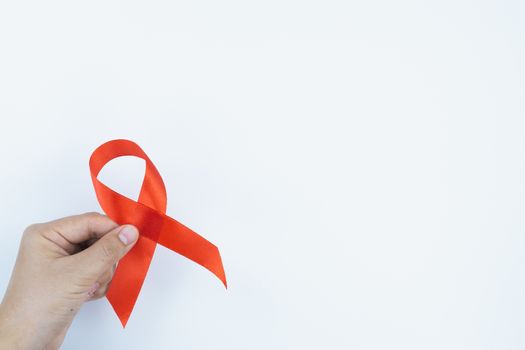 Aids awareness, male hands holding red AIDS awareness ribbon on white background. World Aids Day, Healthcare and medical concept.