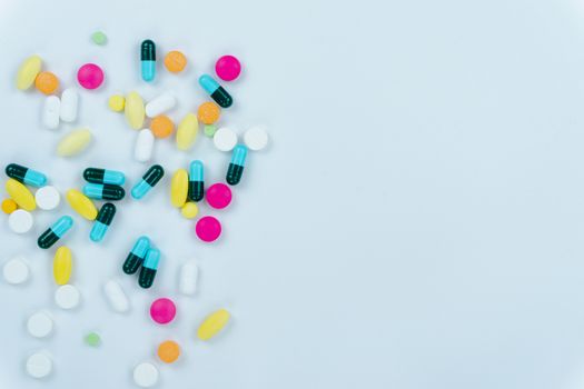 Assorted pharmaceutical medicine pills, tablets and capsules, and bottle on white background. Copy space for text, top view.