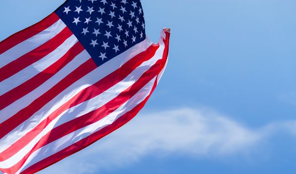 US American flag on blue sky background. For USA Memorial day, Veterans day, Labor day, or 4th of July celebration. Top view, copy space for text.