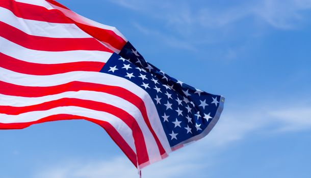 US American flag on blue sky background. For USA Memorial day, Veterans day, Labor day, or 4th of July celebration. Top view, copy space for text.