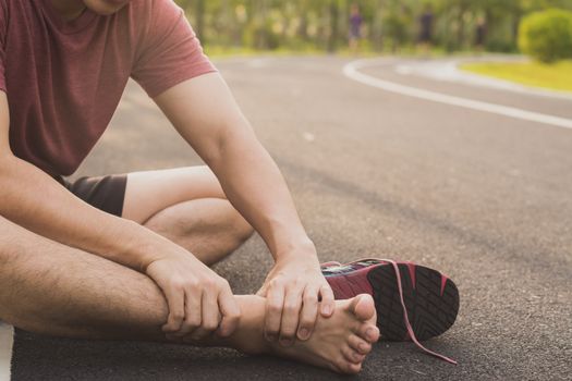 Ankle sprained. Young man suffering from an ankle injury while running at park. Healthcare and sport concept.