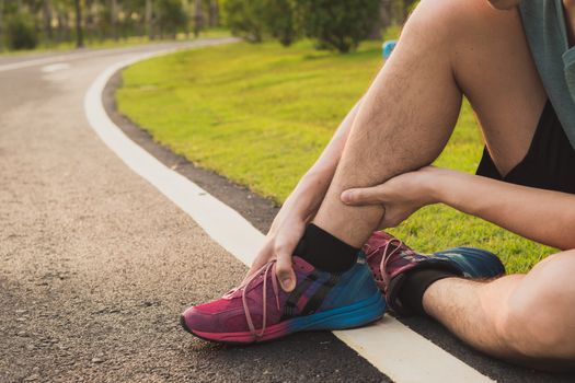 Ankle sprained. Young man suffering from an ankle injury while running at park. Healthcare and sport concept.