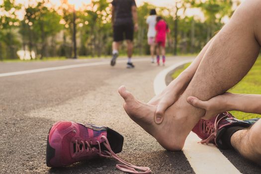 Ankle sprained. Young man suffering from an ankle injury while running at park. Healthcare and sport concept.