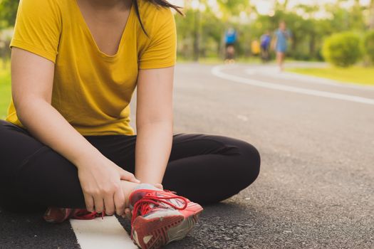 Ankle sprained. Young woman suffering from an ankle injury while jogging and running at the park. Healthcare and sport concept.