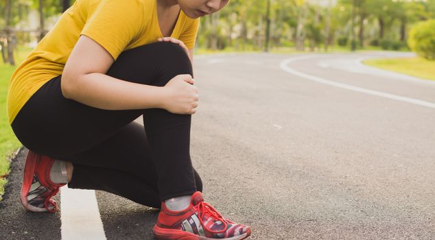 Knee Injuries. Young sport woman holding knee with her hands in pain after suffering muscle injury during a running workout at the park. Healthcare and sport concept.