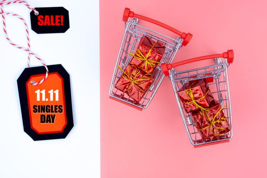 Online shopping of China, The shopping cart and Christmas boxes with red ribbon and shopping tag on a pink and white background with copy space for text. 11.11 single's day sale concept