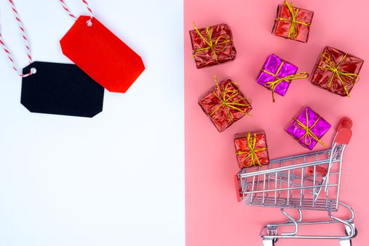 Online shopping of China, The shopping cart and Christmas boxes with red ribbon and shopping tag on a pink and white background with copy space for text. 11.11 single's day sale concept