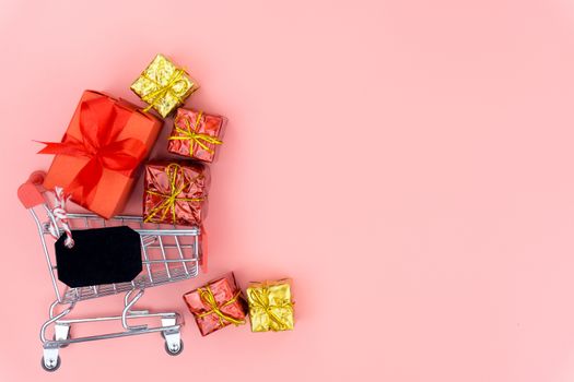 Online shopping of China, The shopping cart and Christmas boxes with red ribbon on a pink background with copy space for text. 11.11 single's day sale concept