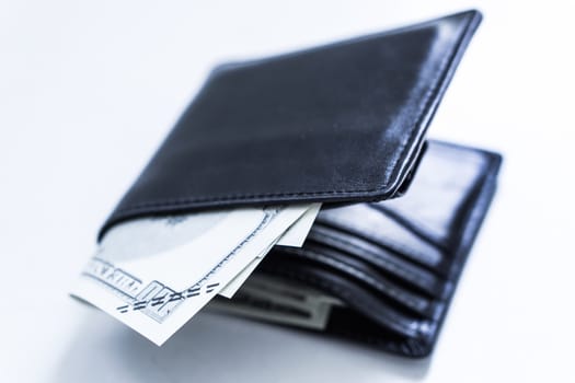 A black leather wallet with money inside on the white table. Money concept, copy space for text.