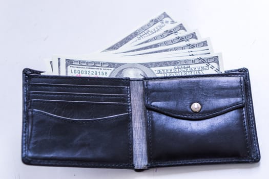 A black leather wallet with money inside on the white table. Money concept, copy space for text.