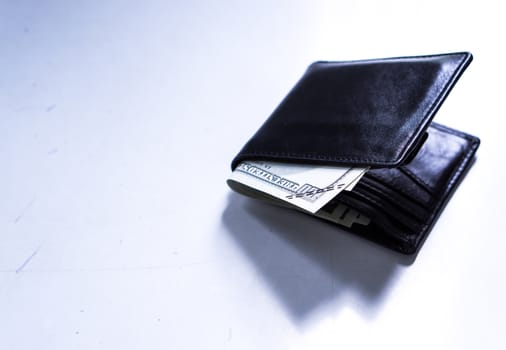 A black leather wallet with money inside on the white table. Money concept, copy space for text.