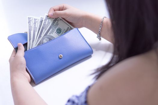 Woman hand taking out the money for payment from the blue wallet. Finance and money concept, copy space for text.