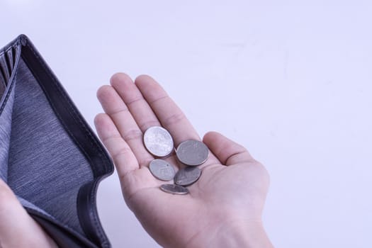 A man holds an empty wallet and coins in his hands on a white background. Finance problem and bankruptcy concept.