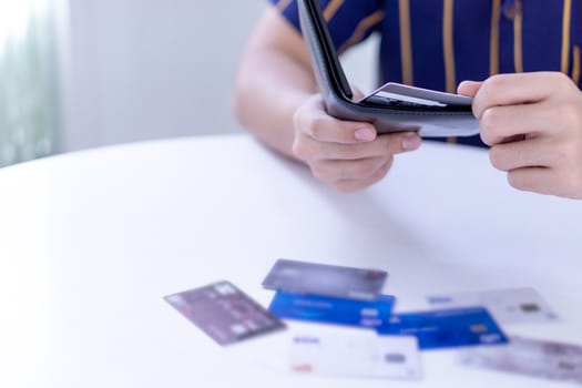 Man hand taking out the credit card for payment from the black leather wallet with many credit card on the white table.  Finance and money concept, copy space for text.