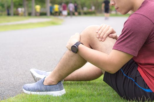 Knee Injuries. Young sport man holding knee with his hands in pain after suffering muscle injury during a running workout at park. Healthcare and sport concept.