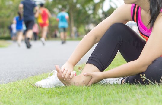 Ankle sprained. Young woman suffering from an ankle injury while jogging and running at the park. Healthcare and sport concept.