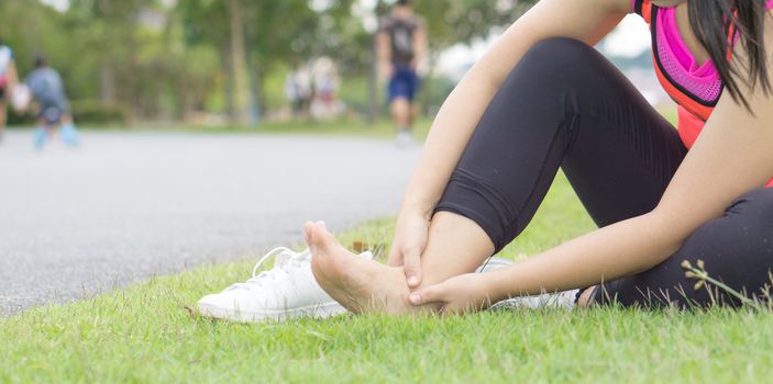 Ankle sprained. Young woman suffering from an ankle injury while jogging and running at the park. Healthcare and sport concept.