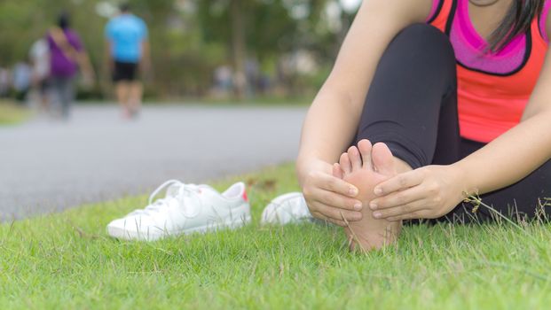 Ankle sprained. Young woman suffering from an ankle injury while jogging and running at the park. Healthcare and sport concept.