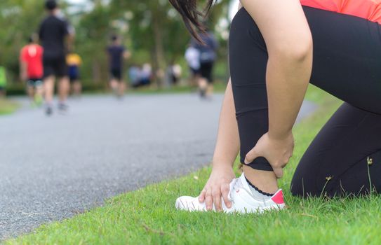 Ankle sprained. Young woman suffering from an ankle injury while jogging and running at the park. Healthcare and sport concept.