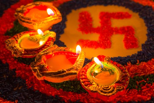 Indian festival Diwali, Diya oil lamps lit on colorful rangoli with Swastika symbol. Hindu traditional. Happy Deepavali.