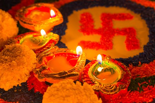 Indian festival Diwali, Diya oil lamps lit on colorful rangoli with Swastika symbol. Hindu traditional. Happy Deepavali.