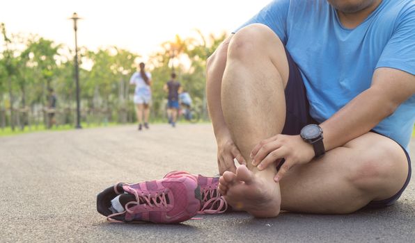 Ankle sprained. Fat man suffering from an ankle injury while running at park. Healthcare and sport concept.