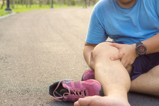 Knee Injuries. Fat man holding knee with his hands in pain after suffering muscle injury during a running workout at park. Healthcare and sport concept.