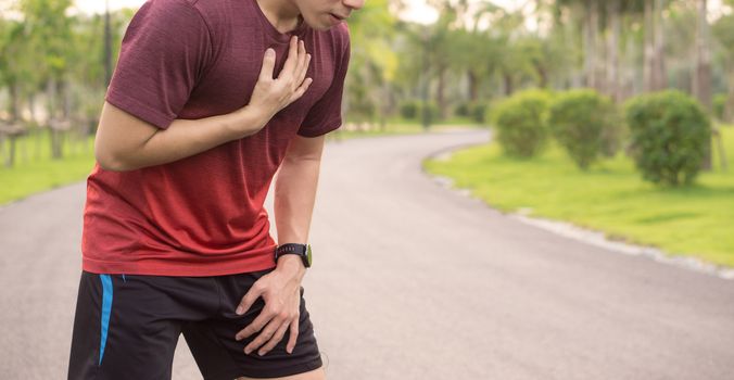 Sport man having heart attack or chest pain after running workout at park. Sport and Health care concept.