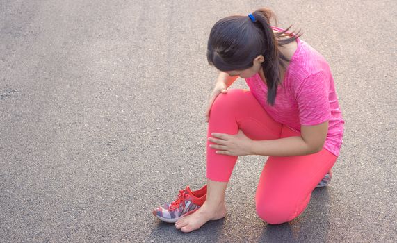 Knee Injuries. Young sport woman holding knee with her hands in pain after suffering muscle injury during a running workout at park. Healthcare and sport concept.