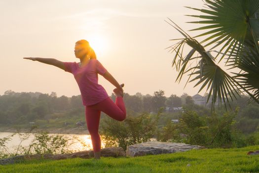 Asian woman practicing yoga in a garden. Healthy lifestyle and relaxation concept