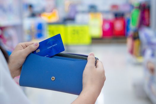 Close up woman hand holding purse, shopping bag and credit card in the shopping mall. Shopping concept.