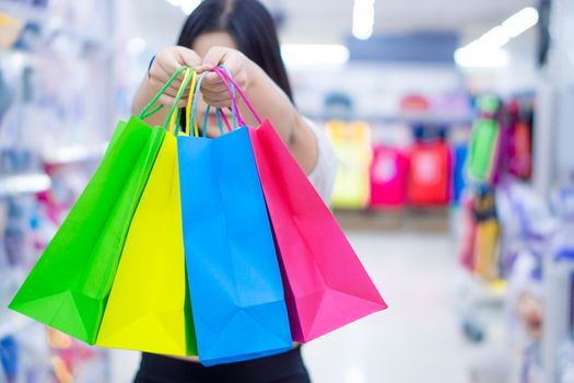 Close up woman hand holding many shopping bags in the shopping mall. Shopping concept.