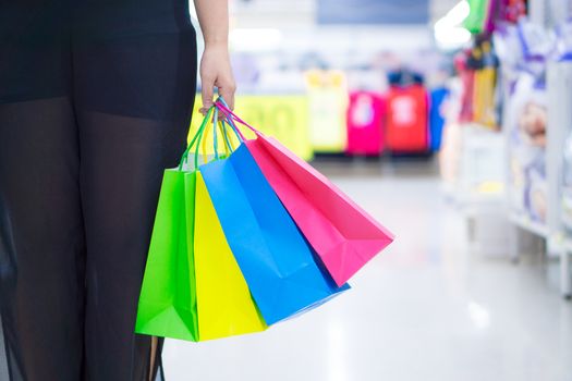 Close up woman hand holding many shopping bags in the shopping mall. Shopping concept.