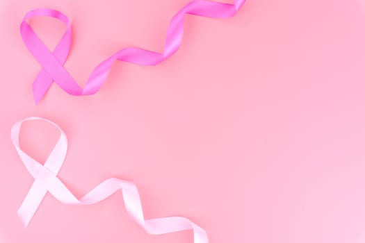 Pink ribbon breast cancer on pink background with copy space for text. Flat lay, top view.