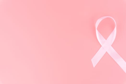 Pink ribbon breast cancer on pink background with copy space for text. Flat lay, top view.