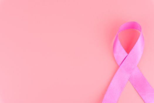 Pink ribbon breast cancer on pink background with copy space for text. Flat lay, top view.