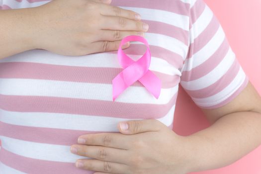 Healthcare, medicine and breast cancer awareness concept. Closeup on woman chest with pink breast cancer awareness ribbon.