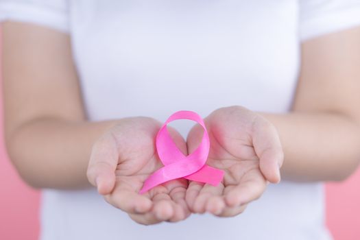 Healthcare, medicine and breast cancer awareness concept. Closeup woman hands holding pink breast cancer awareness ribbon.