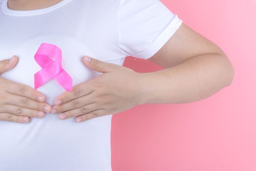 Healthcare, medicine and breast cancer awareness concept. Closeup on woman chest with pink breast cancer awareness ribbon.