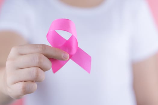 Healthcare, medicine and breast cancer awareness concept. Closeup woman hands holding pink breast cancer awareness ribbon.