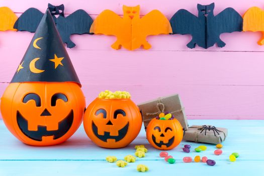 Trick or Treat - Halloween jack o' lantern, candy and rainbow lollipop on pink and blue wooden background with copy space for text. Flat lay, top view