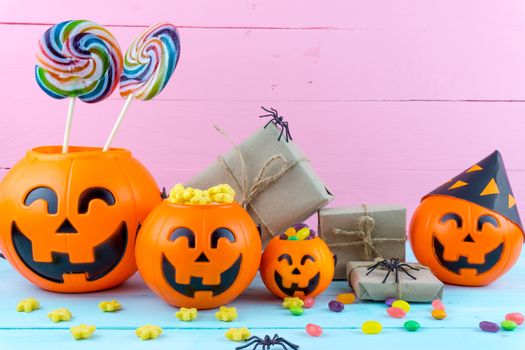 Trick or Treat - Halloween jack o' lantern, candy and rainbow lollipop on pink and blue wooden background with copy space for text. Flat lay, top view