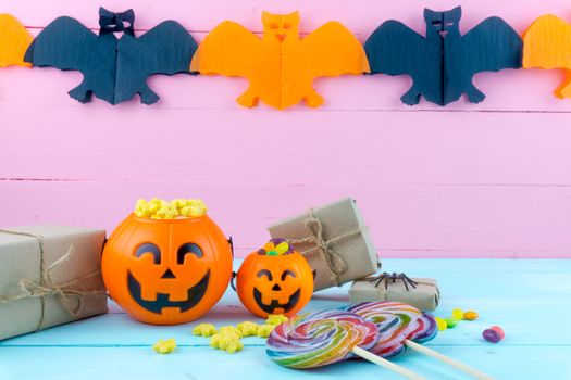 Trick or Treat - Halloween jack o' lantern, candy and rainbow lollipop on pink and blue wooden background with copy space for text. Flat lay, top view
