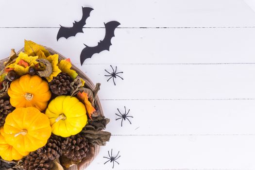 Halloween holiday background with orange pumpkin, ghost, spider and bat on white wooden table with copy space for text. Flat lay, top view