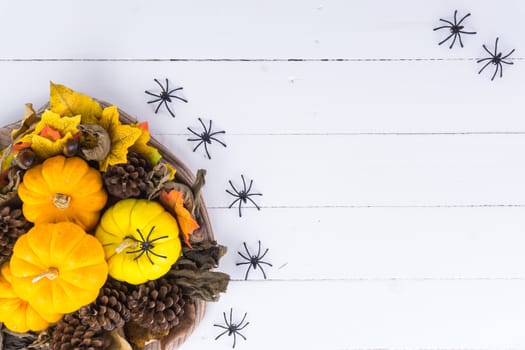 Halloween holiday background with orange pumpkin, ghost, spider and bat on white wooden table with copy space for text. Flat lay, top view