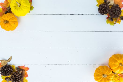 Top view of Autumn maple leaves with pumpkin and pine cone on white wooden background. Thanksgiving day concept. Halloween day.