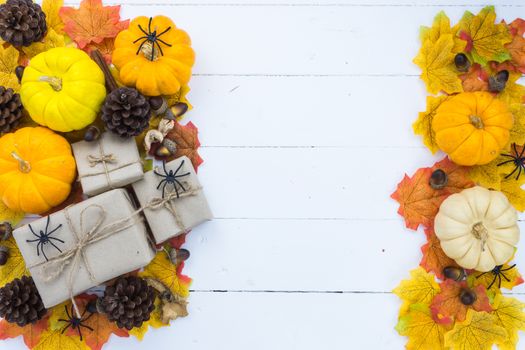 Halloween holiday background with orange pumpkin, ghost, spider and bat on white wooden table with copy space for text. Flat lay, top view