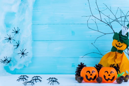 Halloween holiday background with spider, webs, gifts and jack lantern on blue wooden table with copy space for text. Flat lay, top view