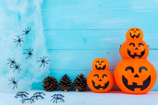 Halloween holiday background with spider, webs, gifts and jack lantern on blue wooden table with copy space for text. Flat lay, top view